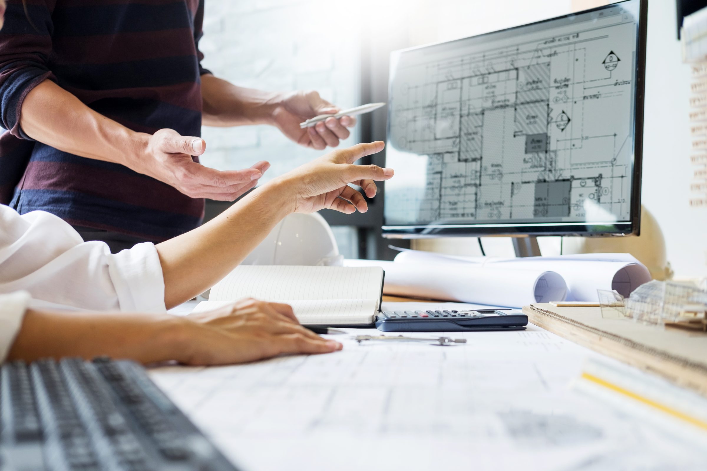 Engineers reviewing technical drawings on a monitor