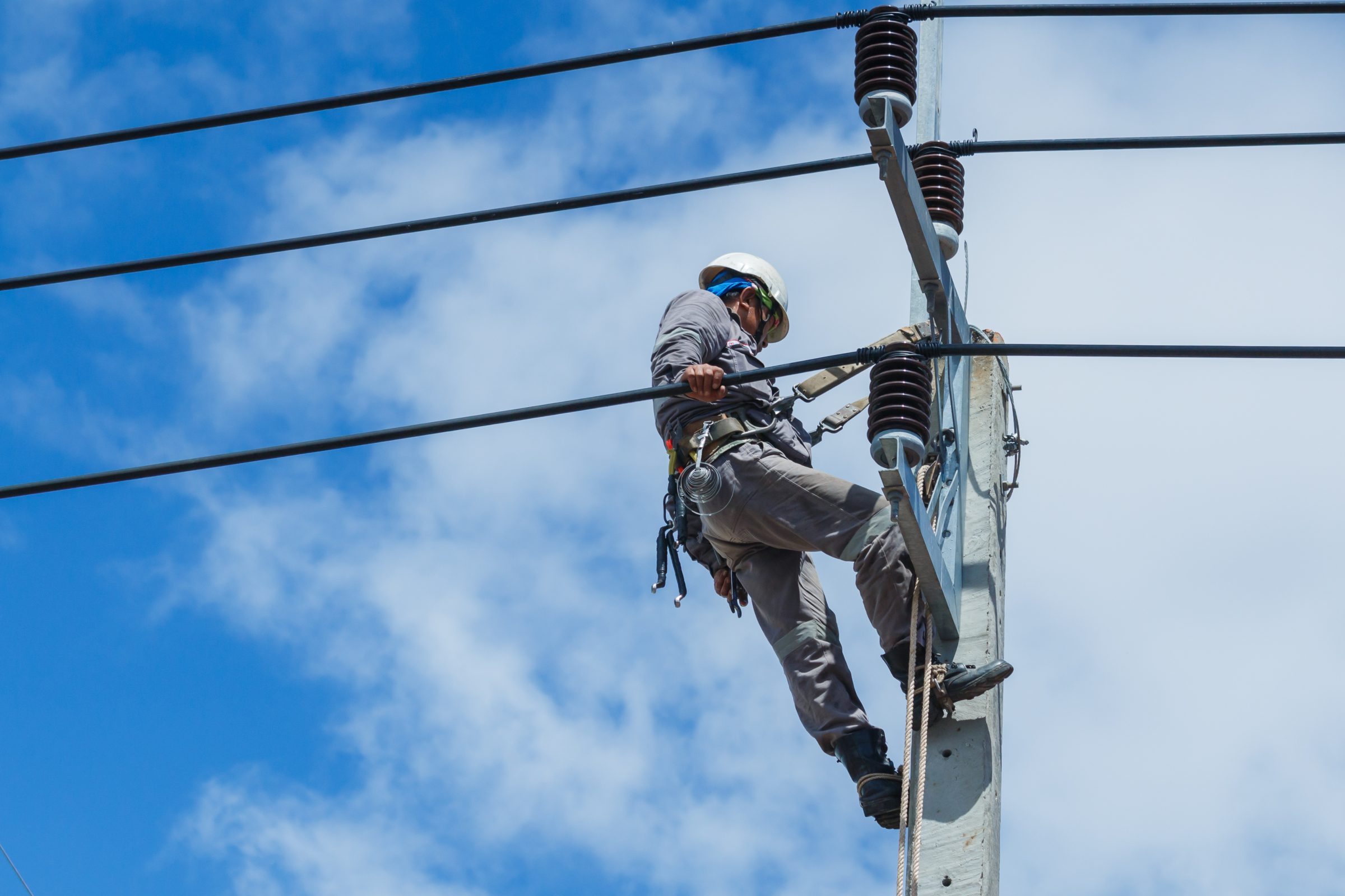 Lineworker climbing a utility pole to reach an insulator