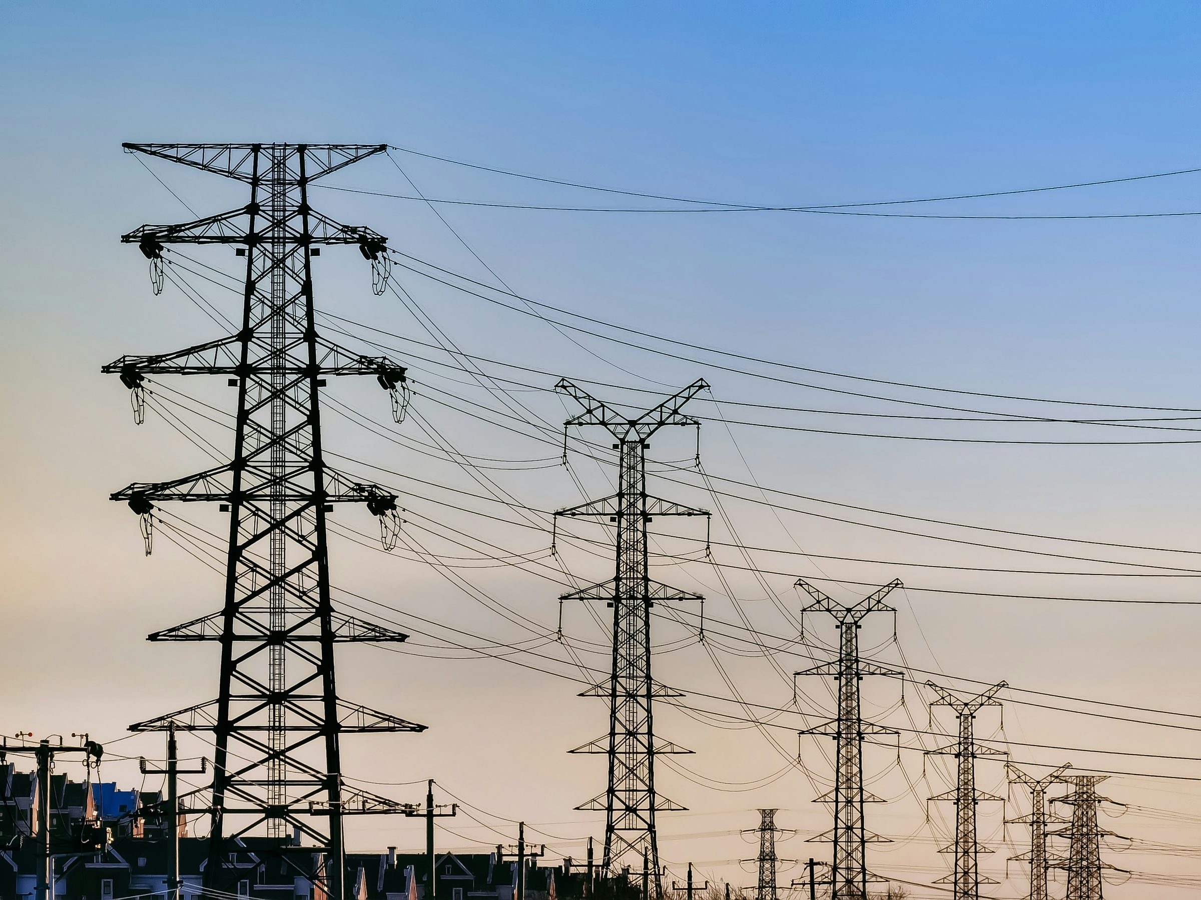 Transmission towers silhouetted against a dusk sky