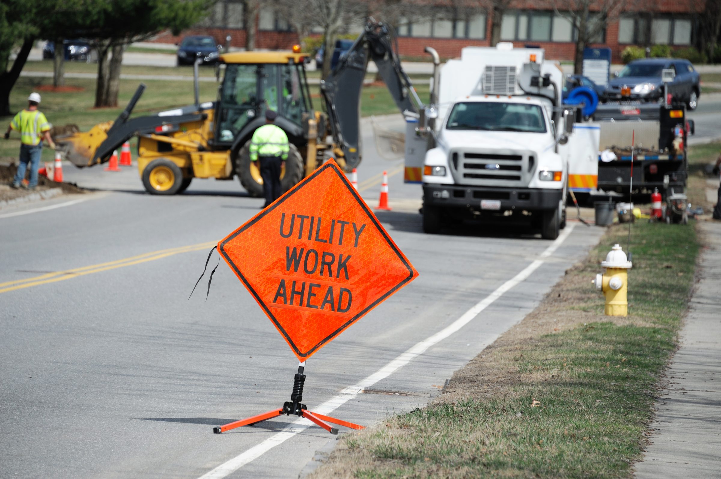 Utility crew at work behind a Utility Work Ahead sign
