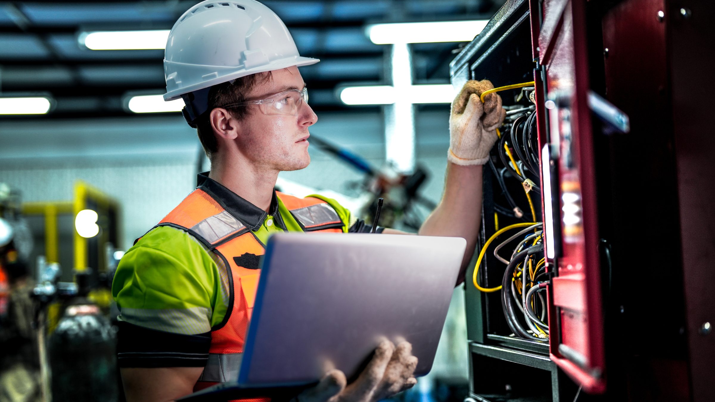 Technician with a laptop working on equipment wiring